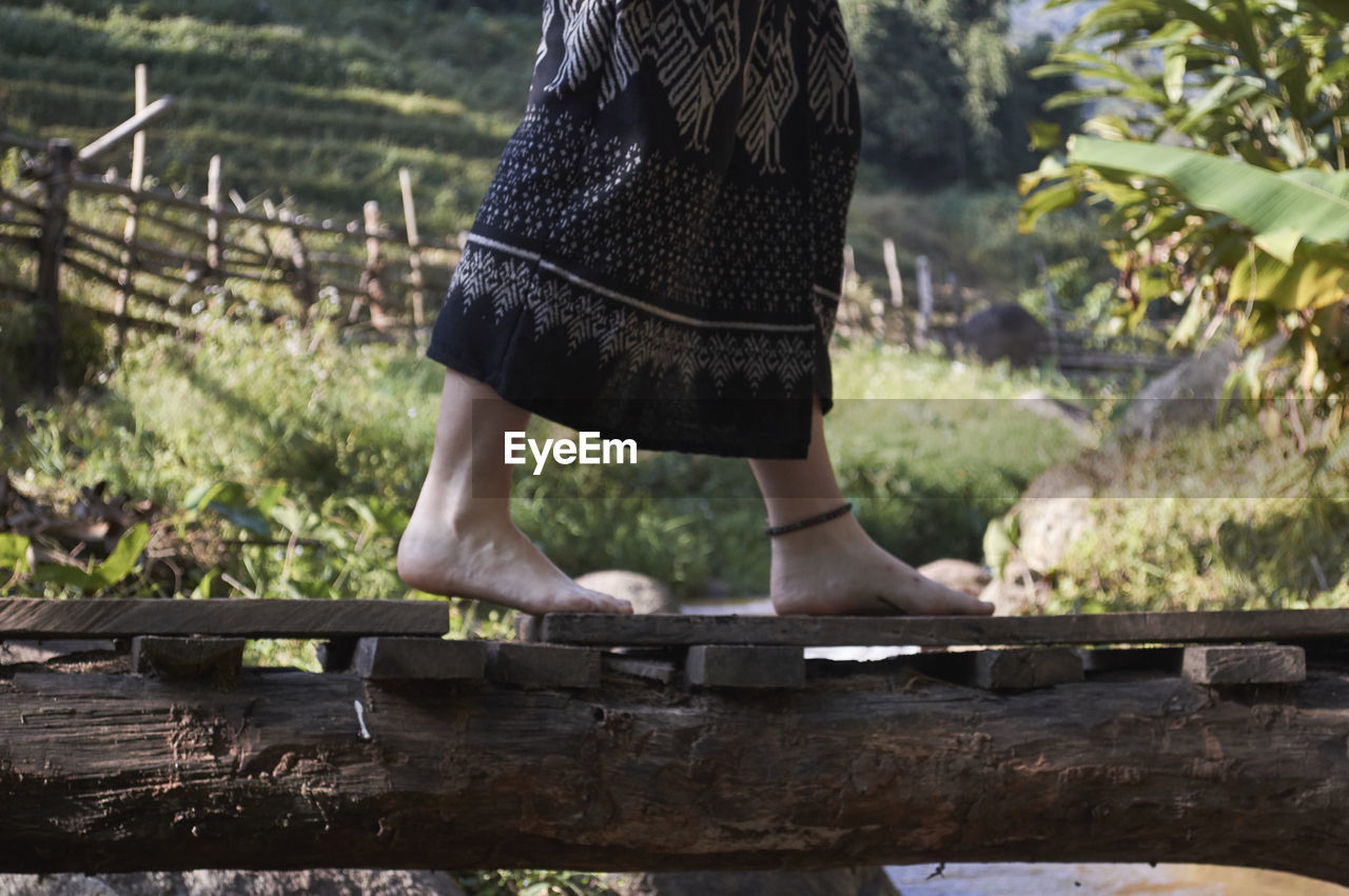 Low section of barefoot woman on footbridge