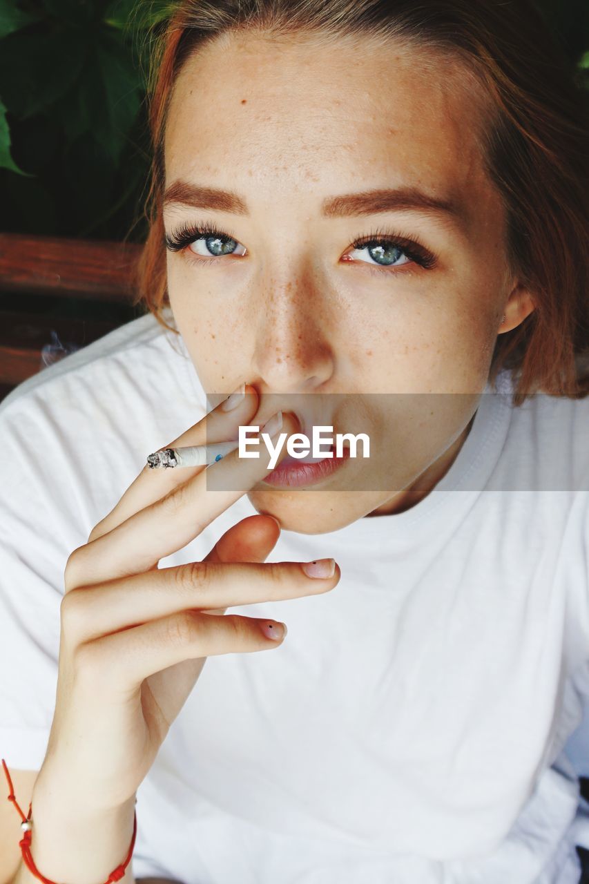 Close-up portrait of beautiful woman smoking cigarette