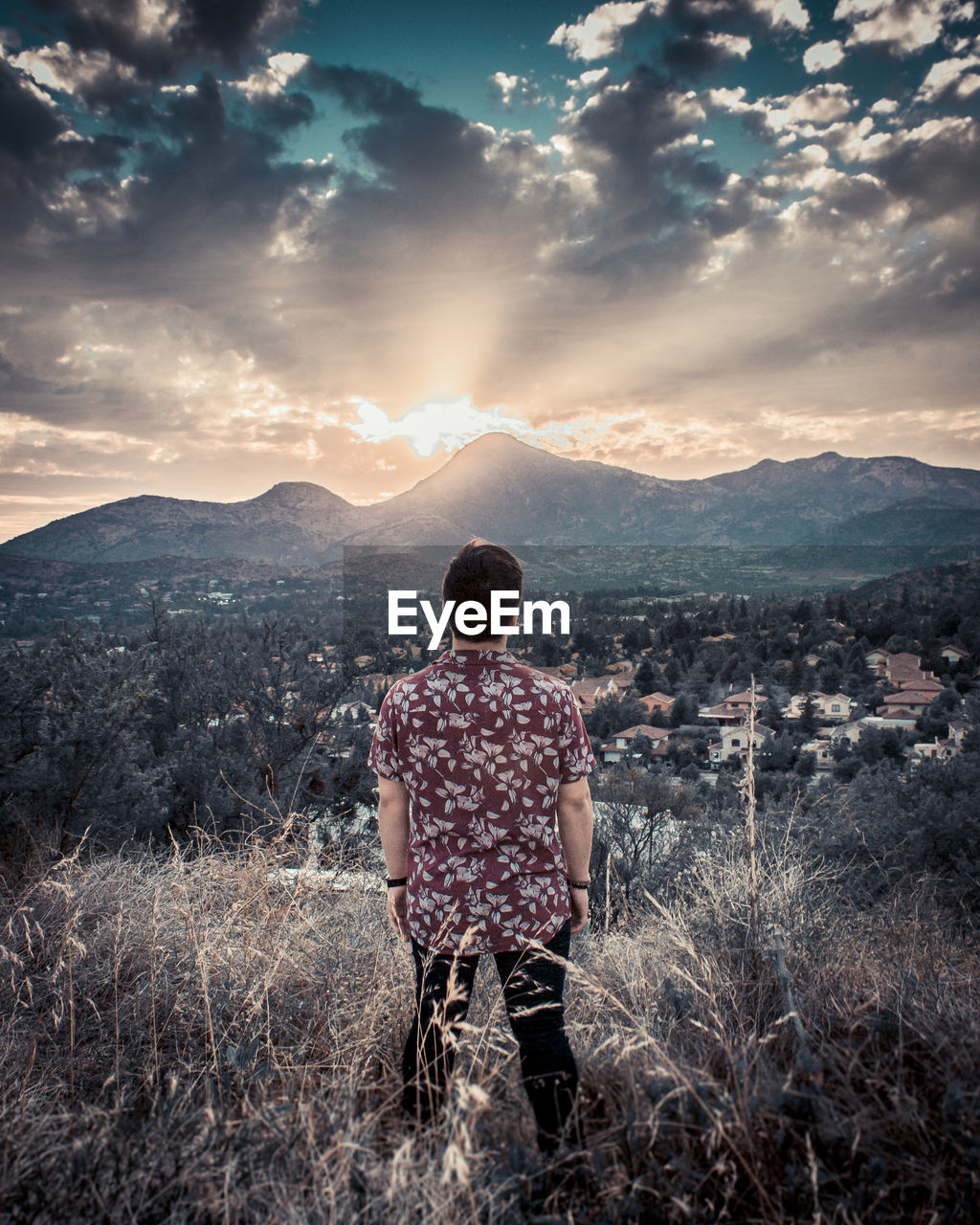 REAR VIEW OF MAN LOOKING AT MOUNTAINS