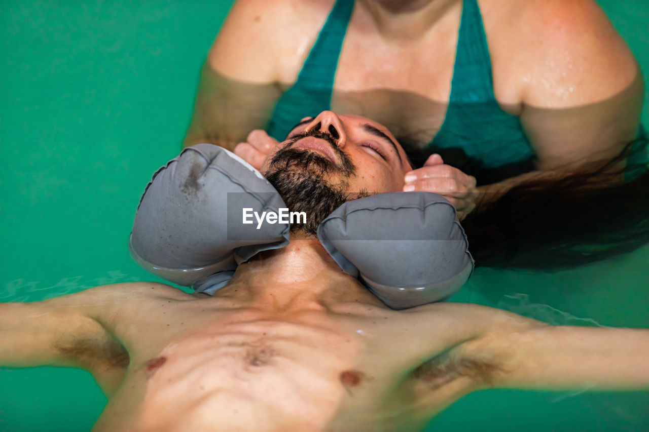 Midsection of couple swimming in pool