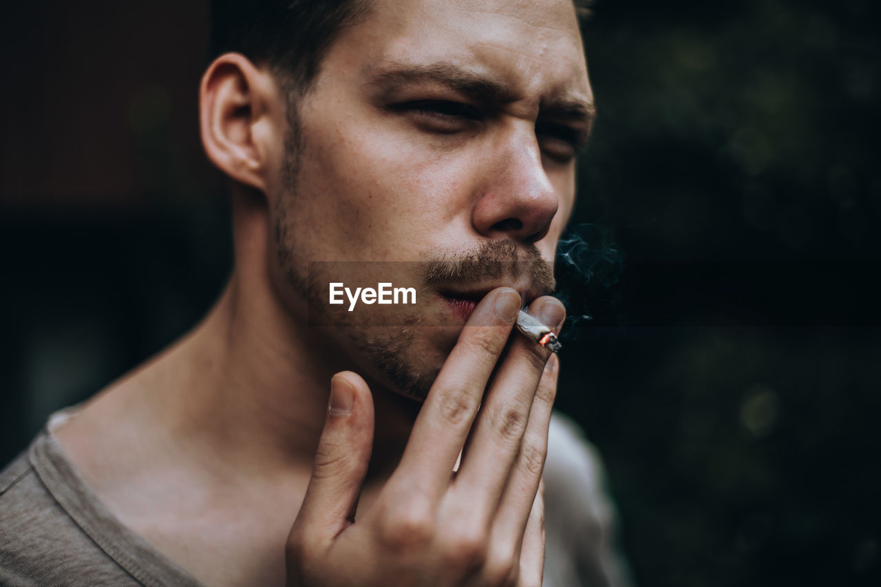 Young man smoking cigarette outdoors