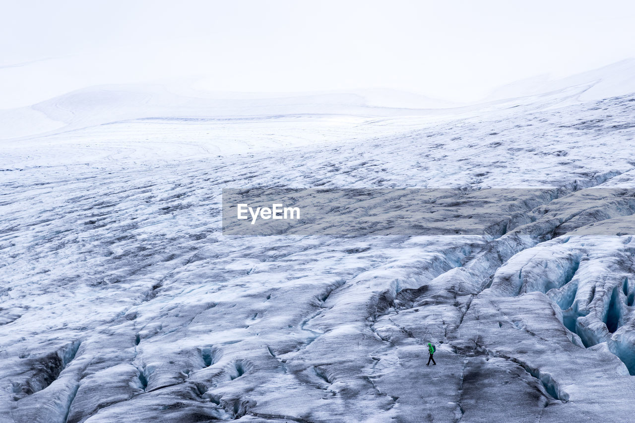 High angle view of hiker walking on snowcapped landscape