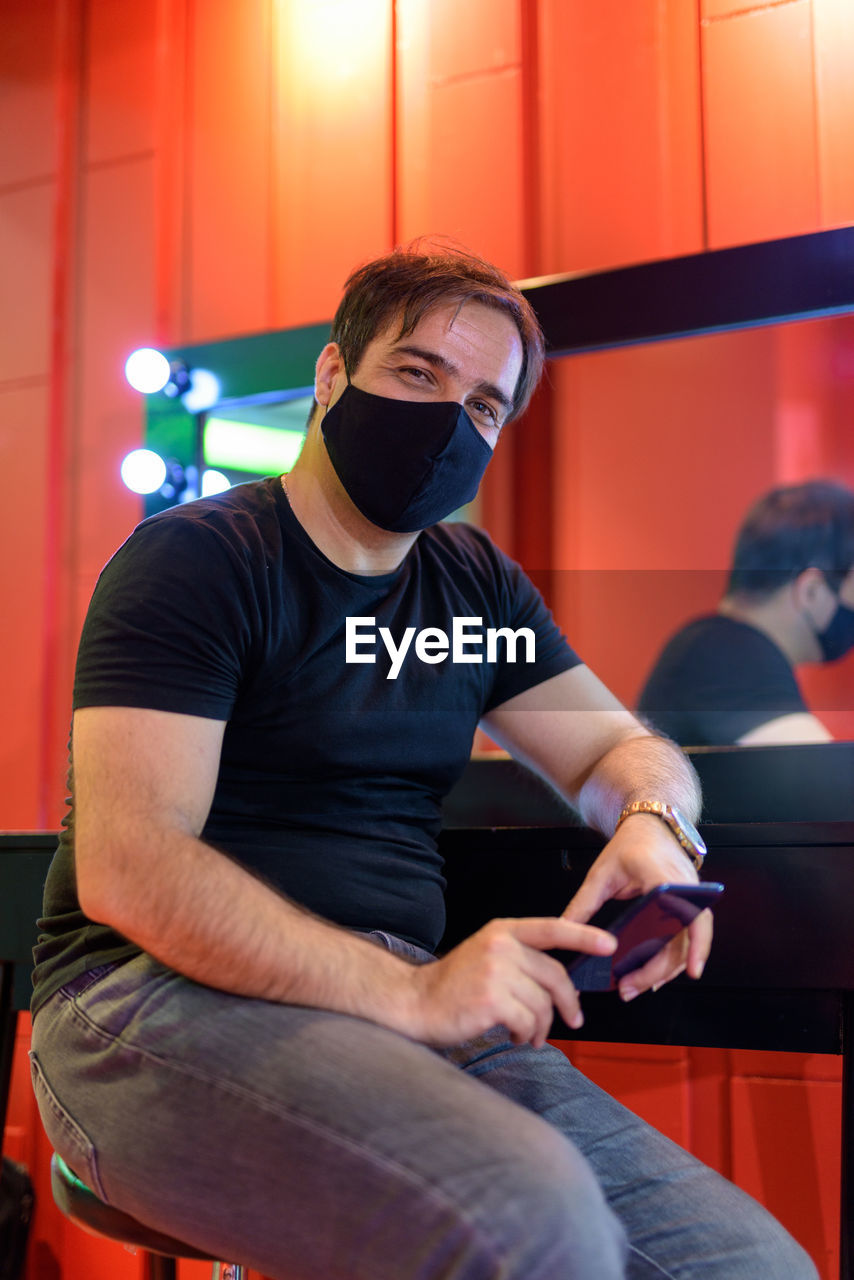 Portrait of man wearing mask sitting at cafe