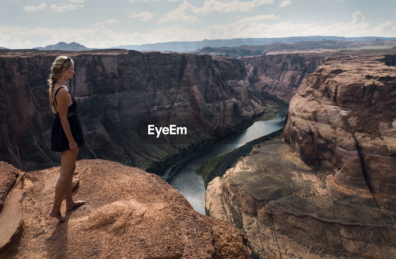 Side view of woman standing on cliff against horseshoe bend