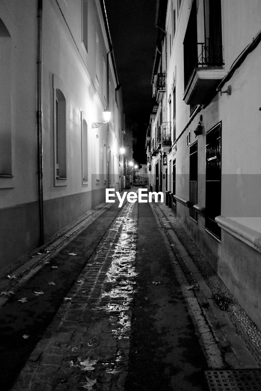 Narrow street amidst buildings at night