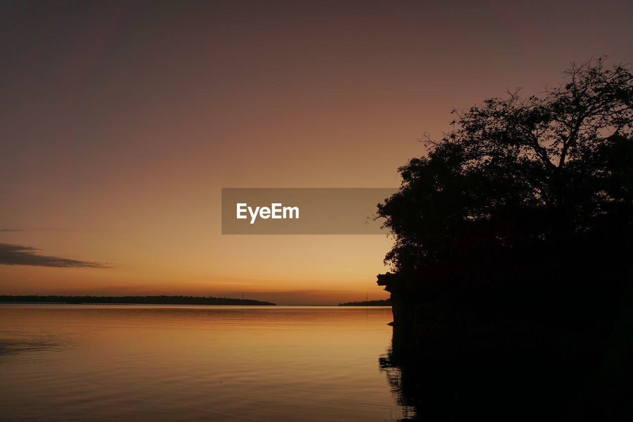 water, sky, sunset, beauty in nature, tranquility, scenics - nature, tree, tranquil scene, nature, sea, reflection, silhouette, plant, dawn, no people, orange color, idyllic, land, afterglow, beach, evening, cloud, horizon, outdoors, environment, horizon over water, landscape, non-urban scene, copy space, sun