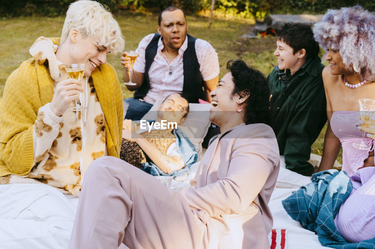 Happy friends from lgbtq community laughing together during dinner party in back yard