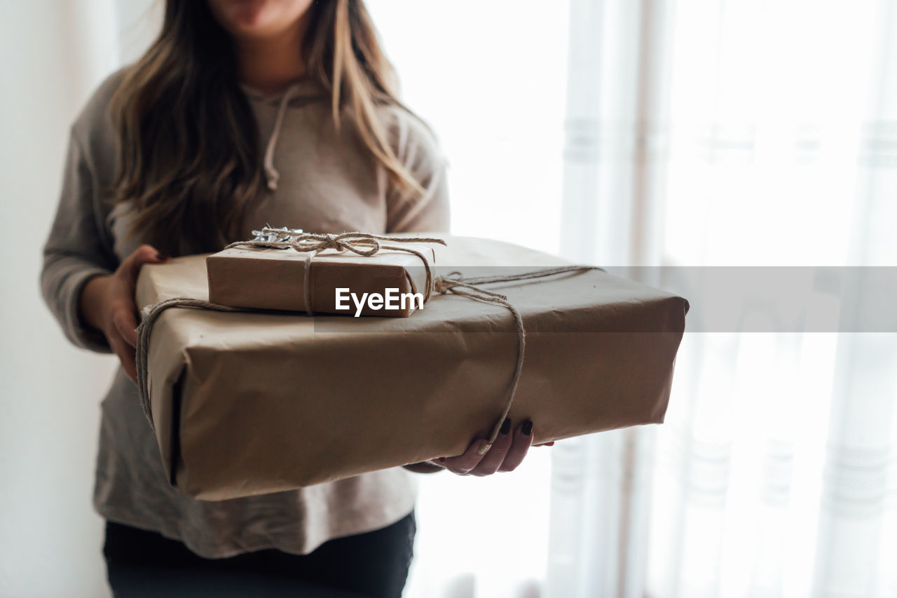 Woman holding christmas gift standing at home