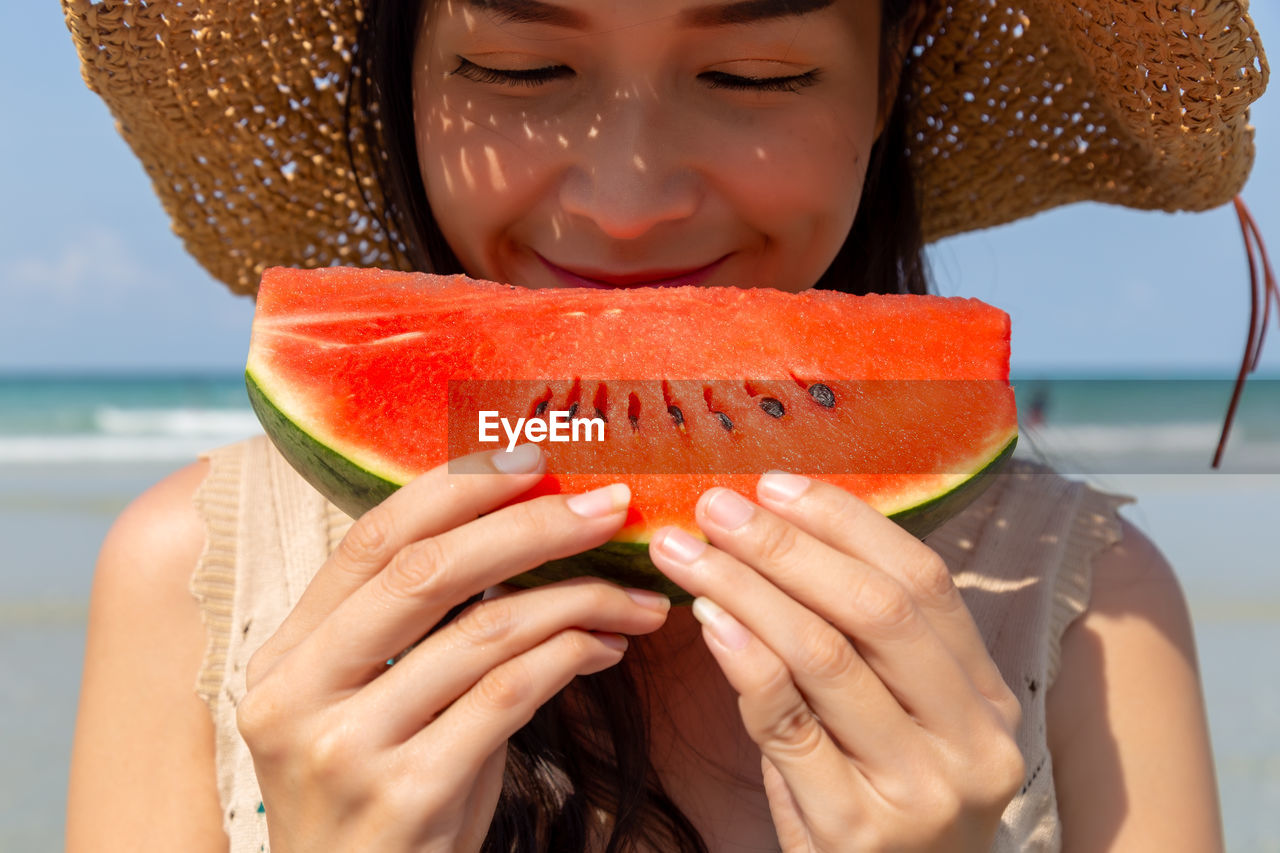 Midsection of woman eating watermelon at beach