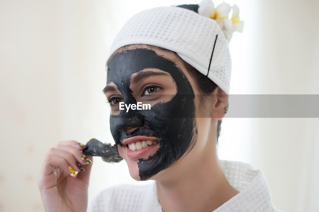 Young woman removing facial mask from face in spa