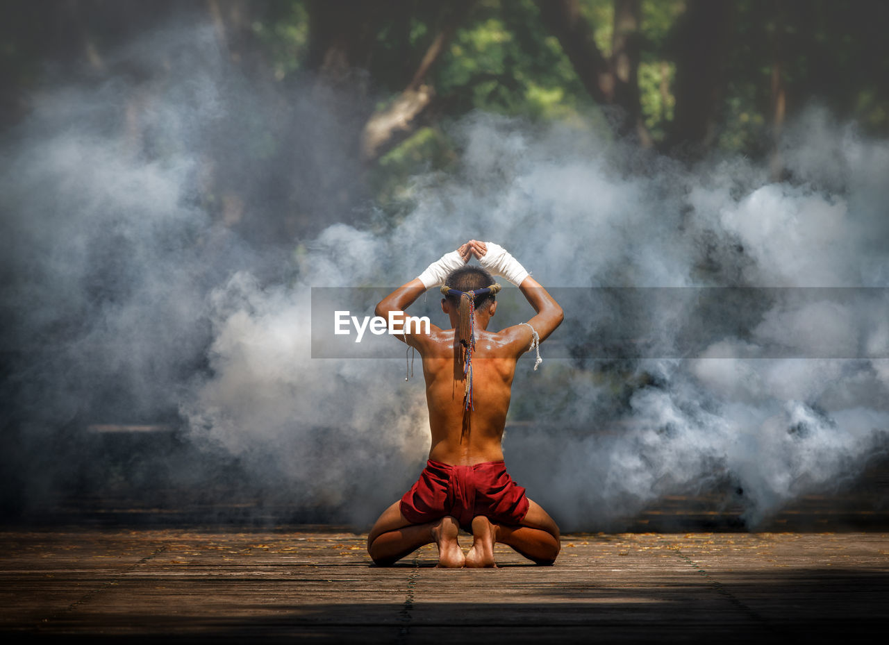 Full length rear view of shirtless warrior in forest