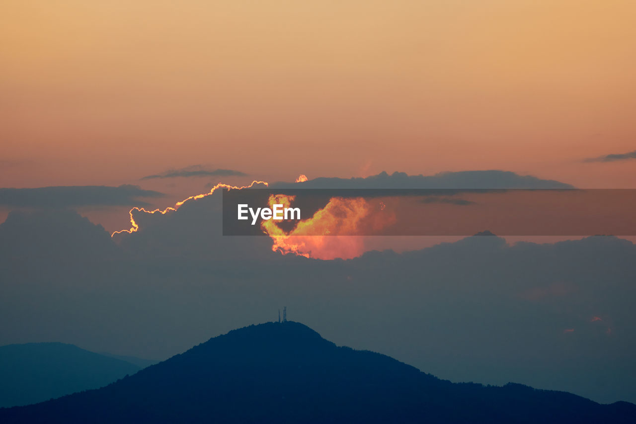 Scenic view of silhouette mountains against romantic sky at sunset