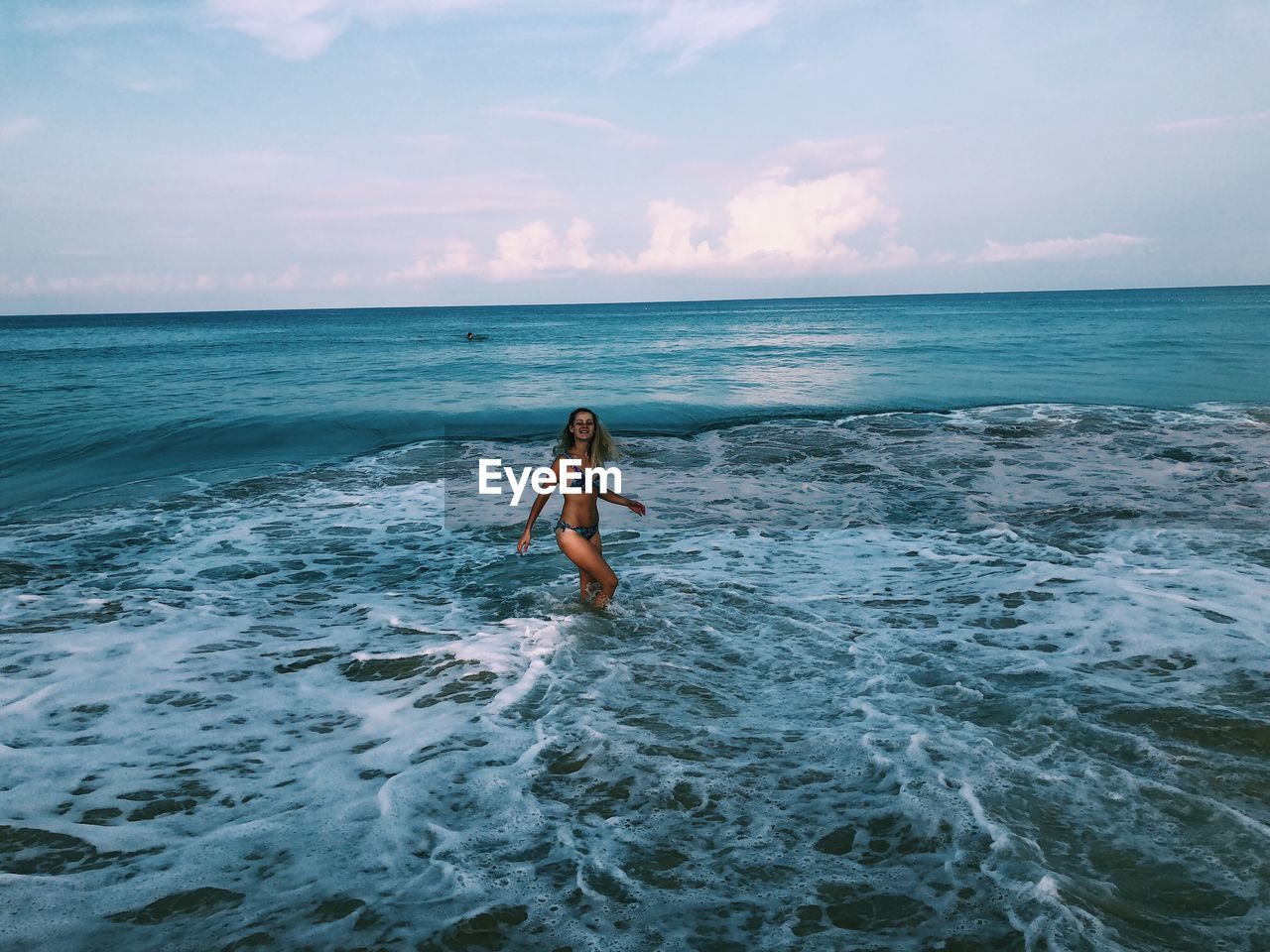 Woman wading in sea against sky