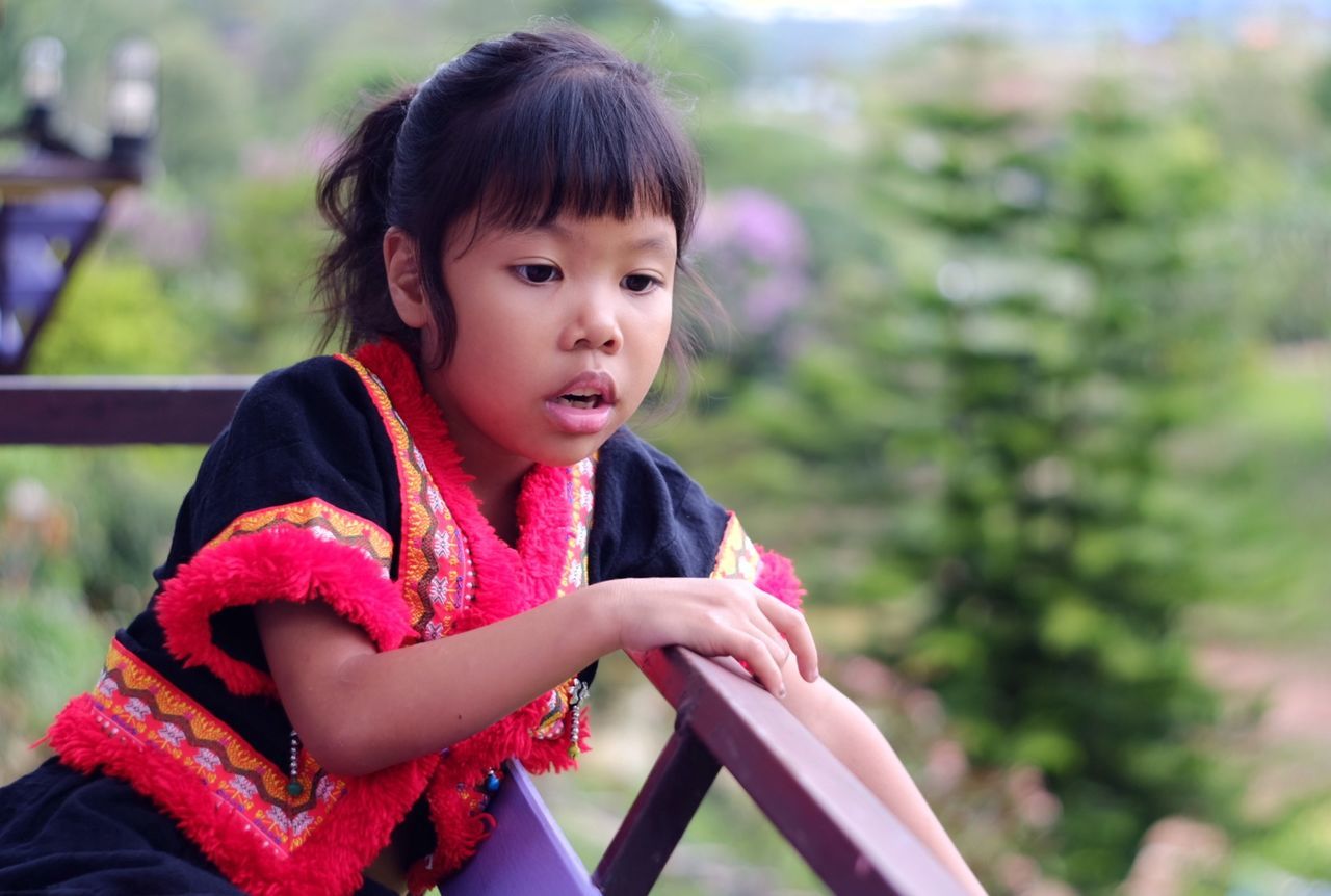 Girl looking away while standing by railing in balcony
