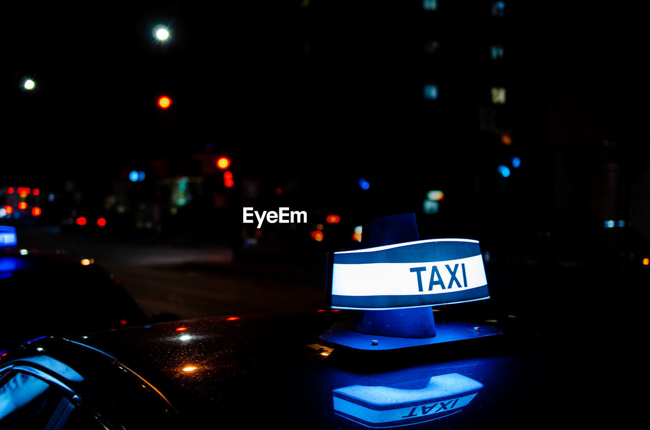 INFORMATION SIGN ON ILLUMINATED CITY STREET AT NIGHT