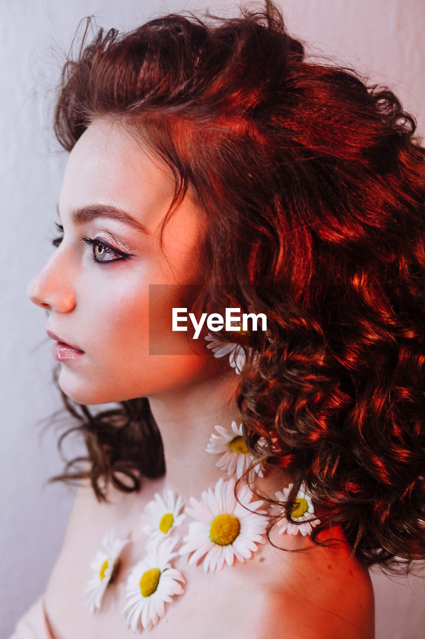 Close-up of beautiful young woman wearing flowers and make-up