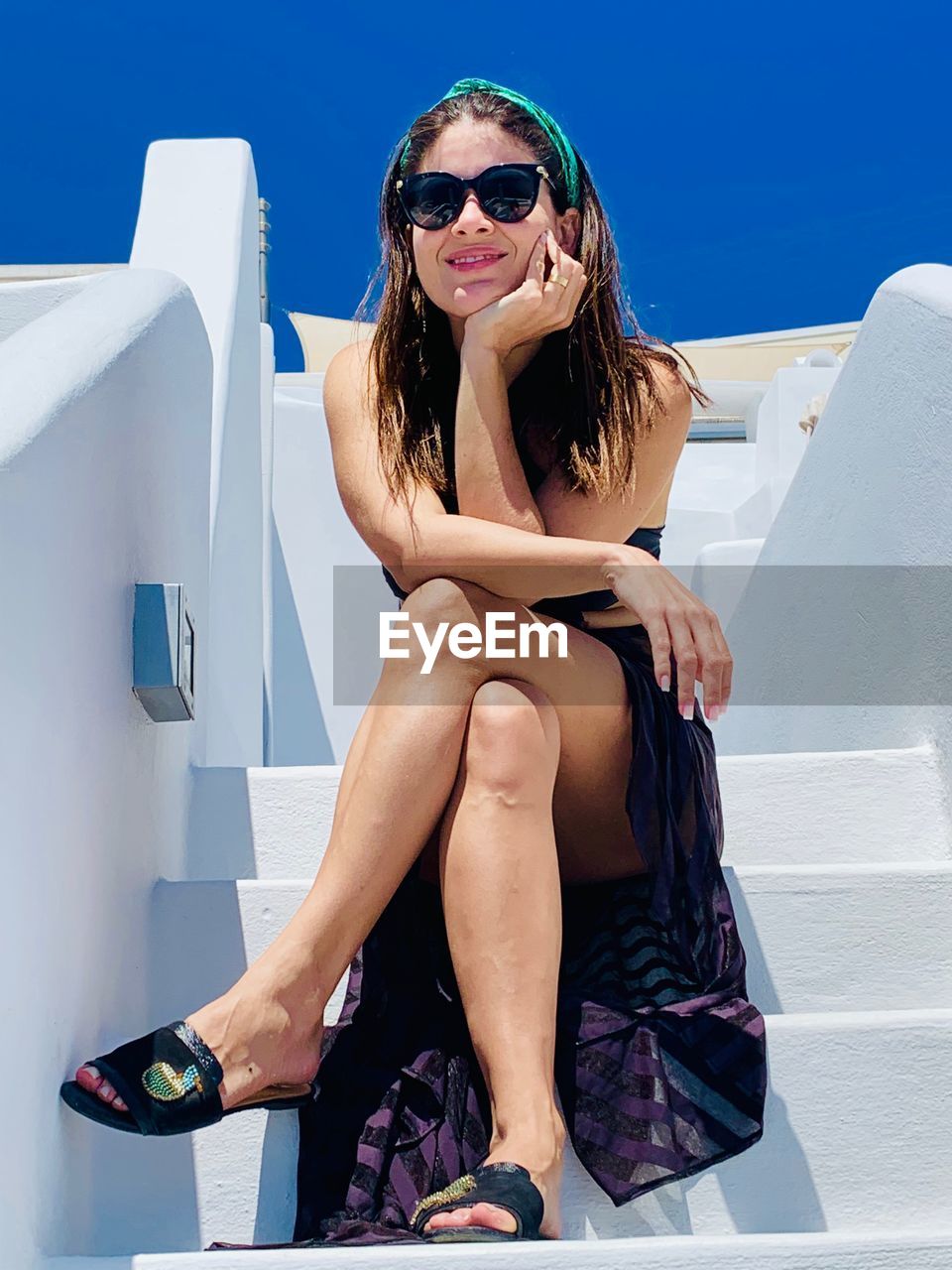 YOUNG WOMAN WEARING SUNGLASSES SITTING ON A OUTDOORS