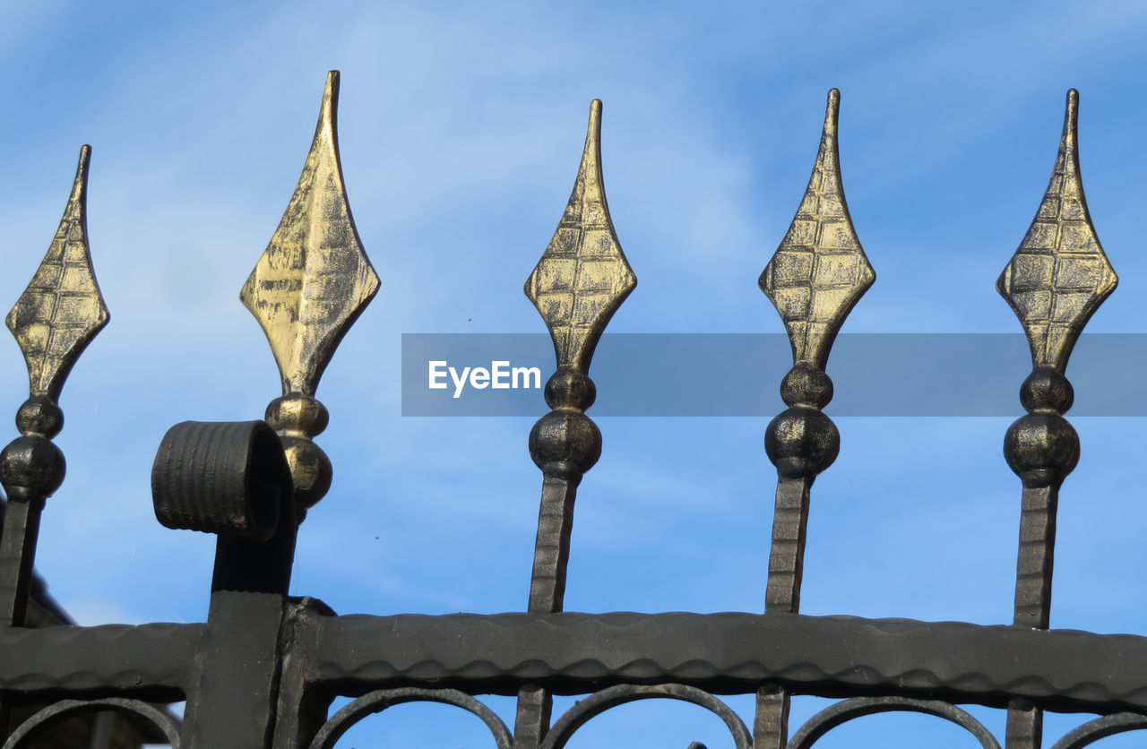 Low angle view of metal fence against sky