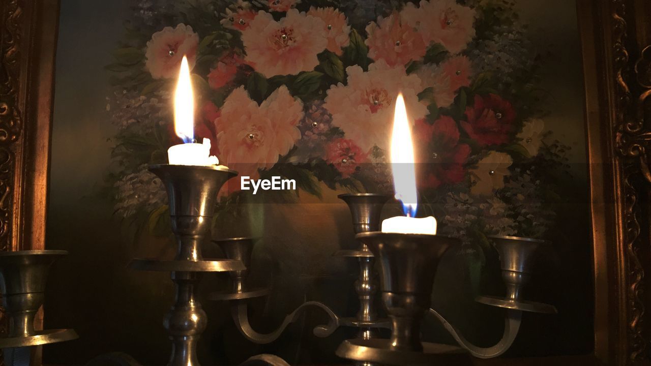 Close-up of burning candles in front of picture frame