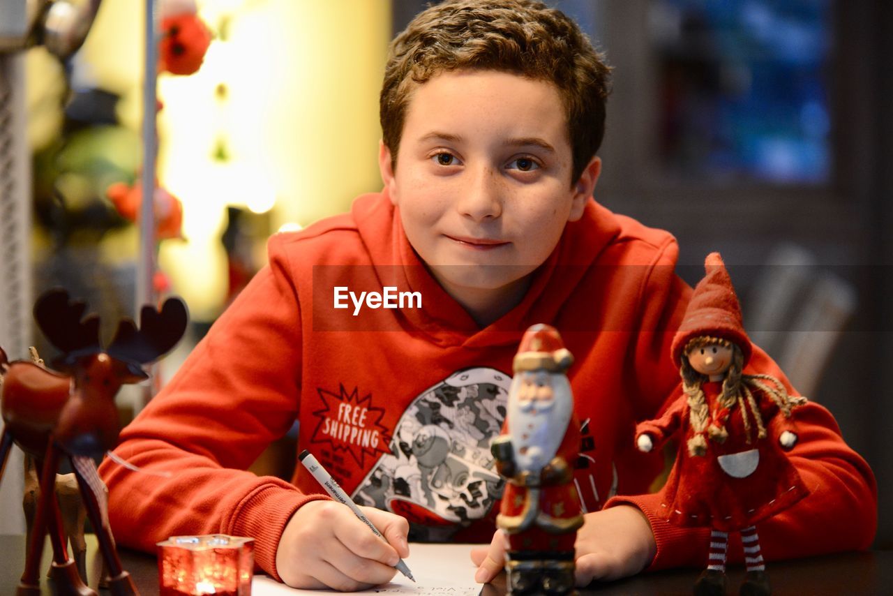 Portrait of boy writing on paper at home during christmas