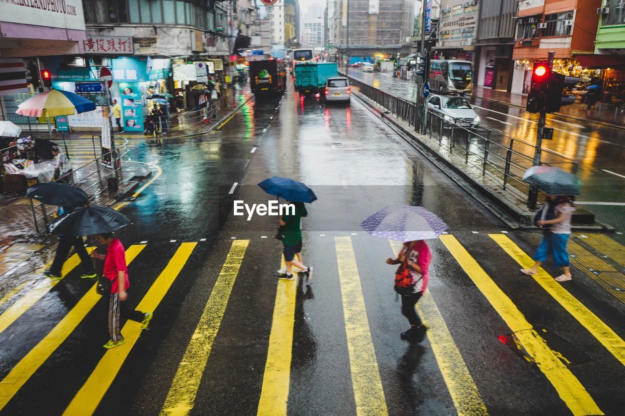 GROUP OF PEOPLE WALKING ON WET ROAD