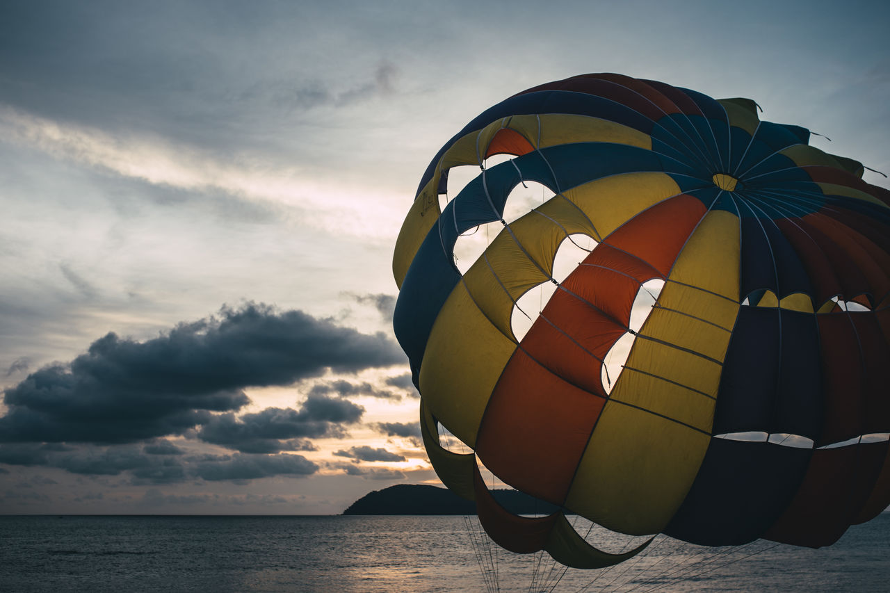 Close-up of parachute by sea against cloudy sky