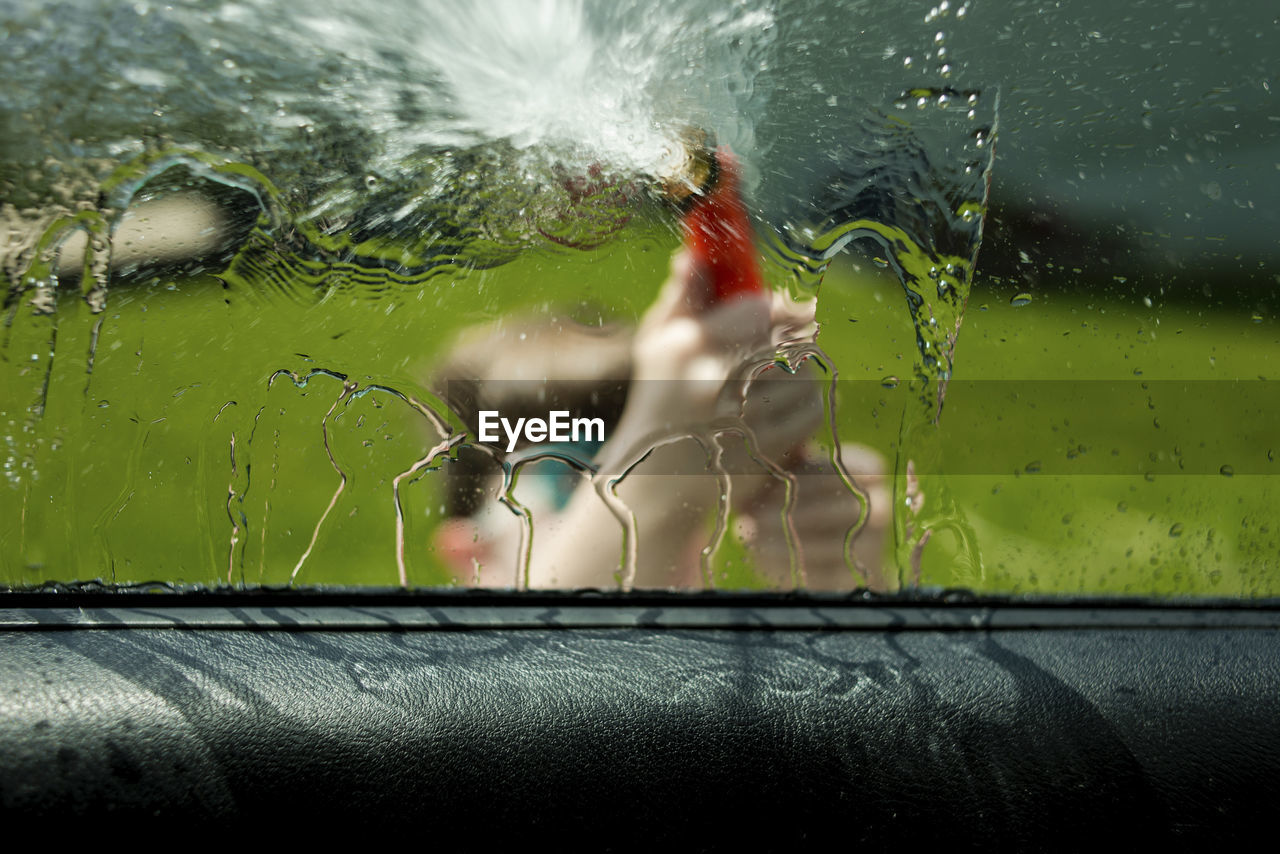 Boy washing car seen through window