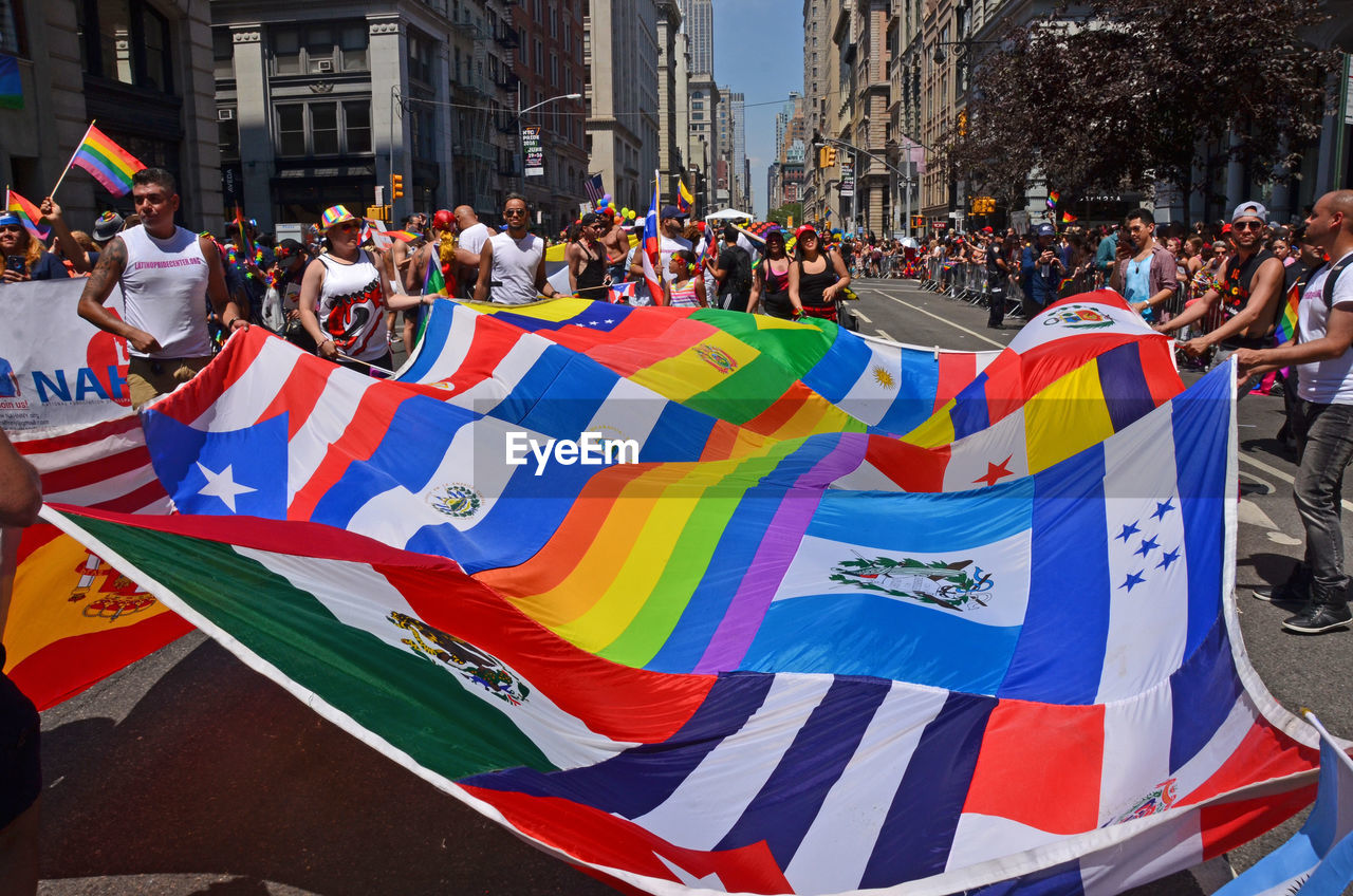 People holding flags and walking during gay pride parade on street
