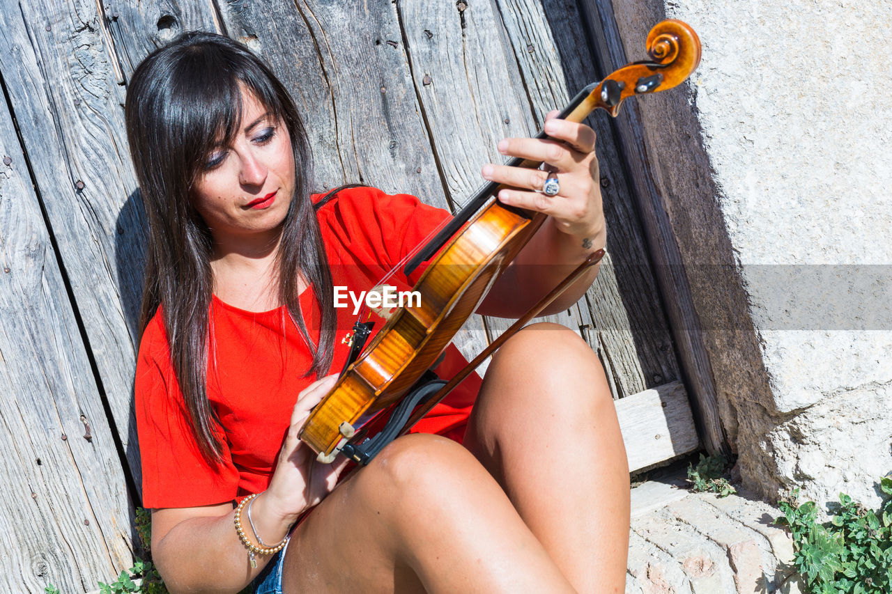 Portrait of young woman playing violin outdoors