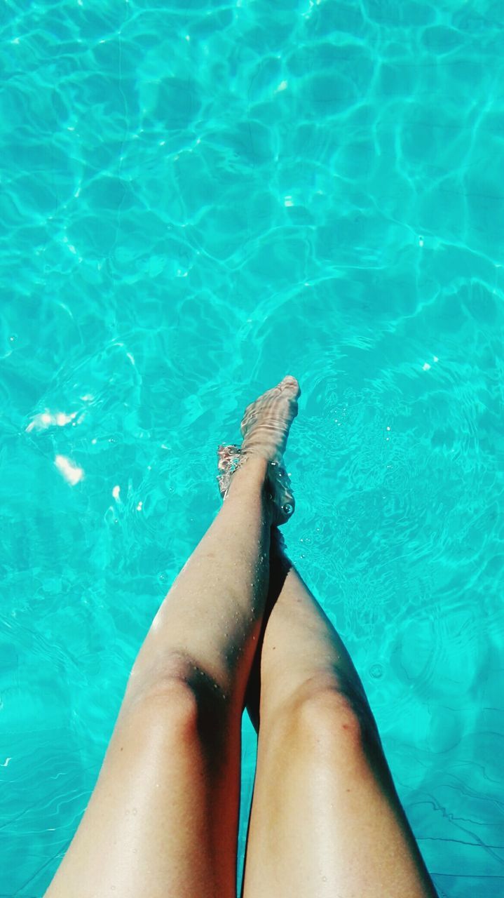 Low section of woman legs in swimming pool