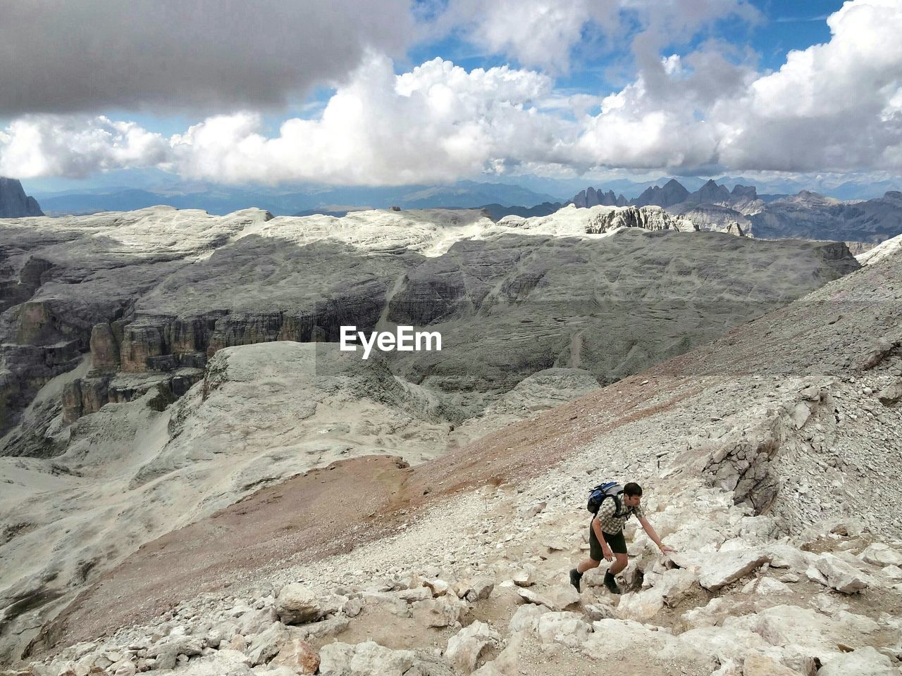 High angle view of man hiking on mountains against cloudy sky