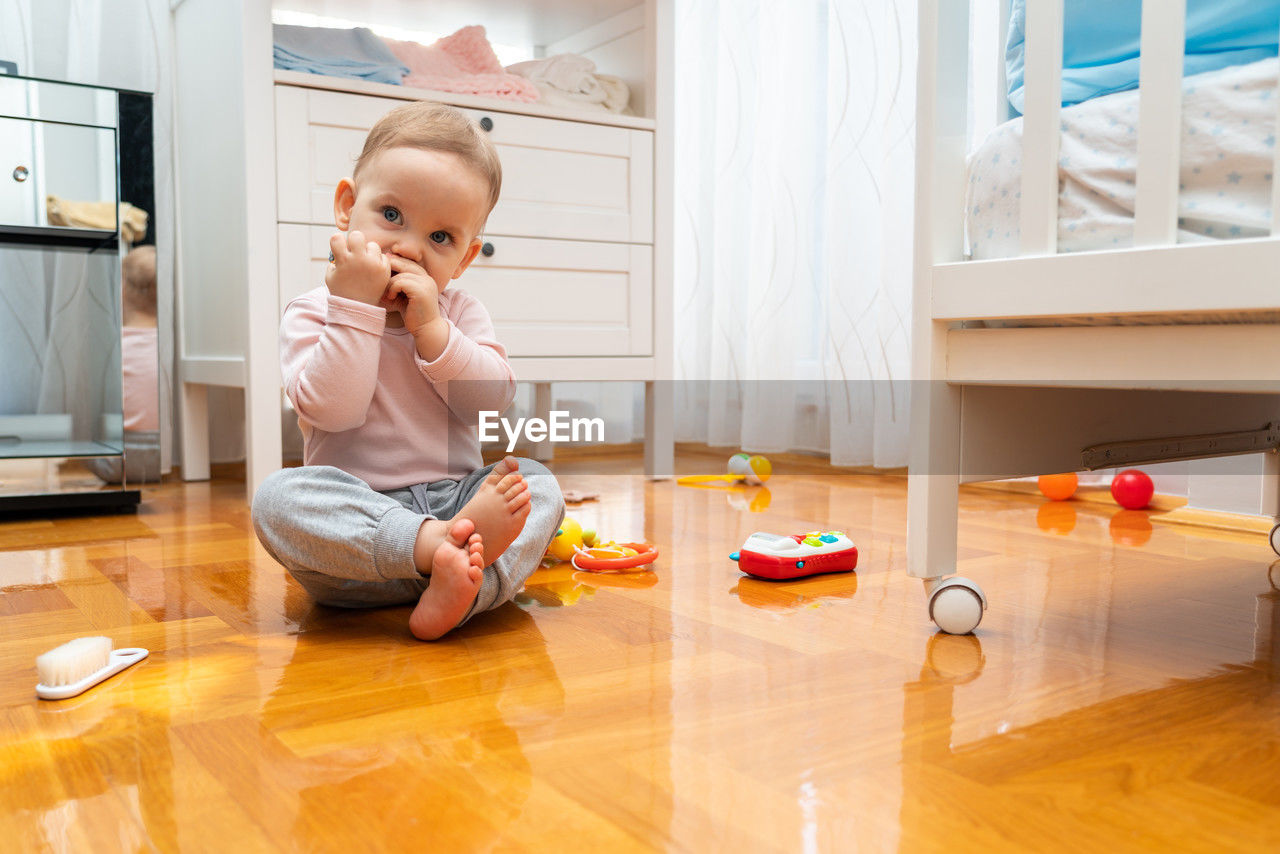 portrait of boy playing with toy blocks while sitting on floor at home