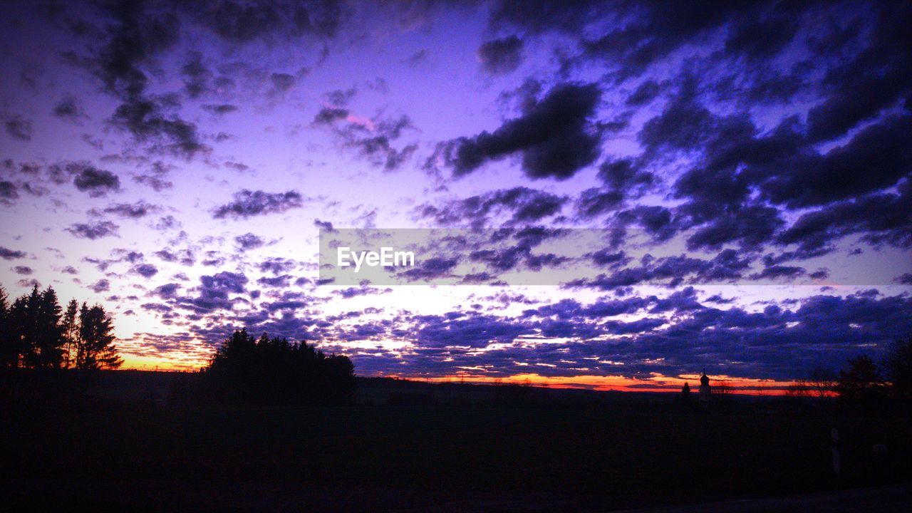 SILHOUETTE LANDSCAPE AGAINST DRAMATIC SKY DURING SUNSET