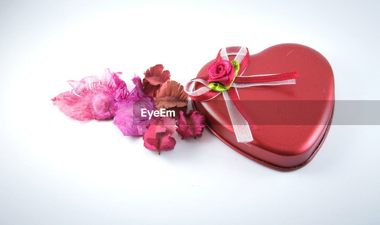 High angle view of heart shape chocolate box by dried flower on white background