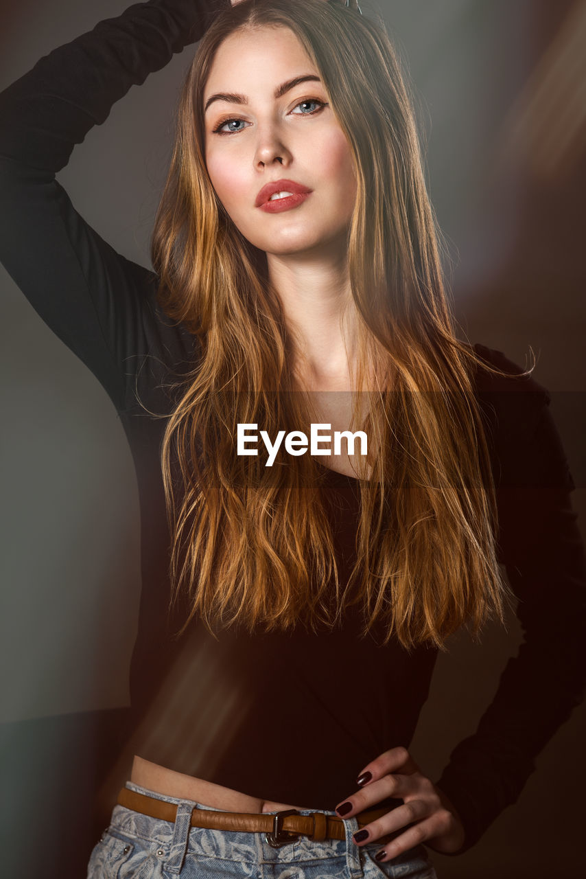 Portrait of beautiful young woman standing against wall