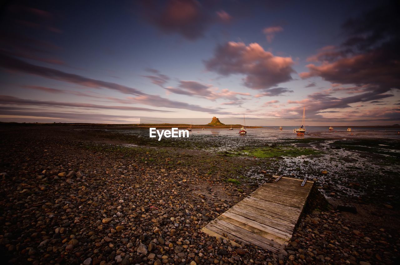 View of pebbled beach against cloudy sky at dusk