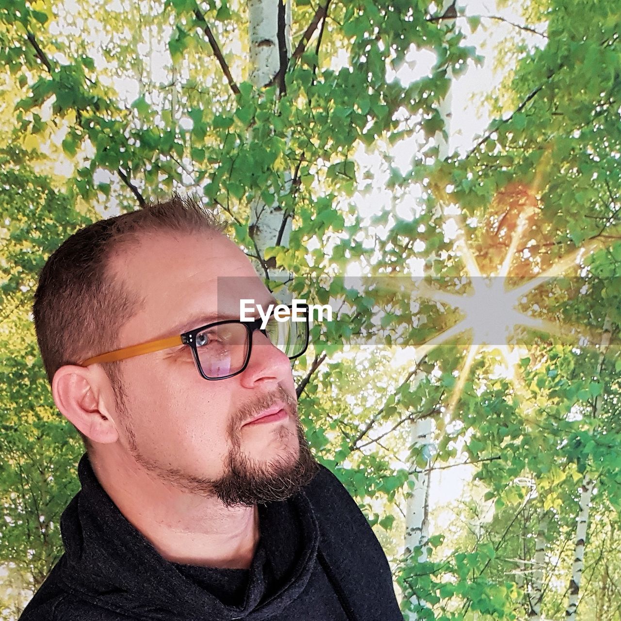 PORTRAIT OF YOUNG MAN WITH EYEGLASSES ON PLANTS