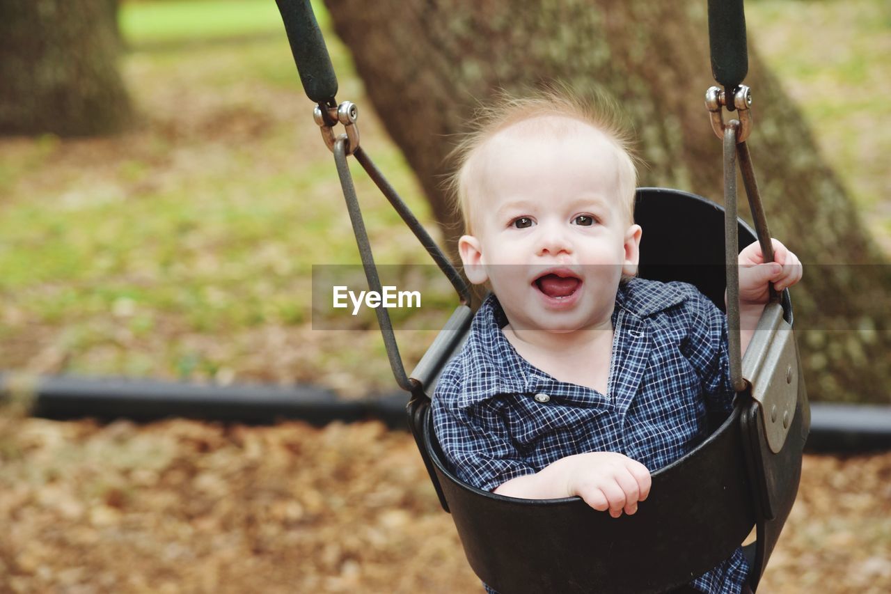 Portrait of boy on swing at park