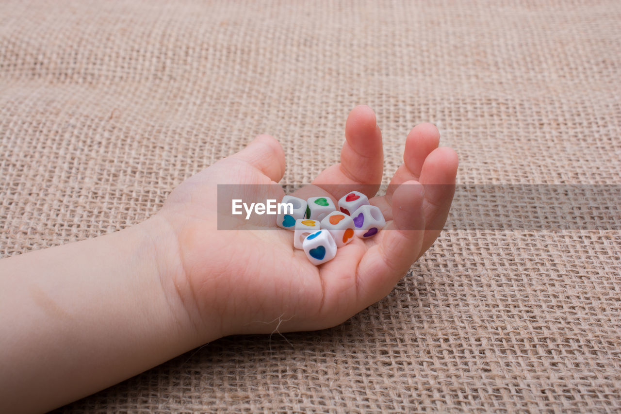 Cropped hand of child holding colorful toys on table