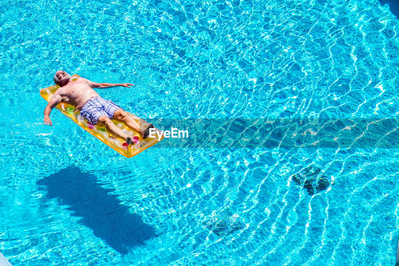 High angle view of man relaxing in swimming pool