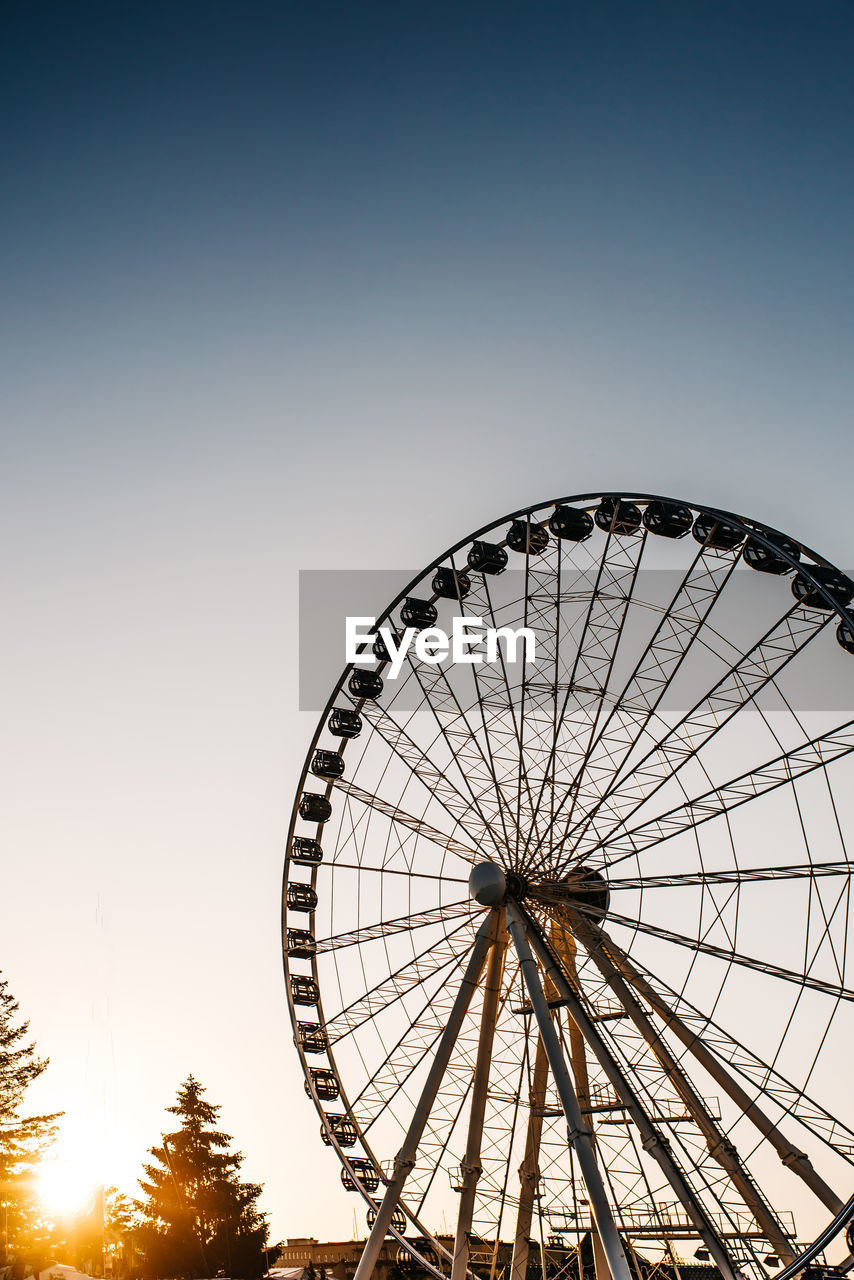 LOW ANGLE VIEW OF FERRIS WHEEL AGAINST CLEAR SKY DURING SUNSET