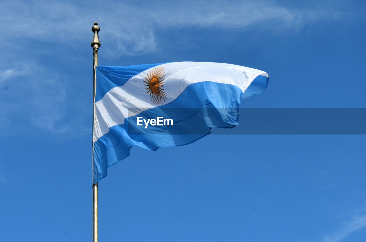 Low angle view of argentinian flag against blue sky