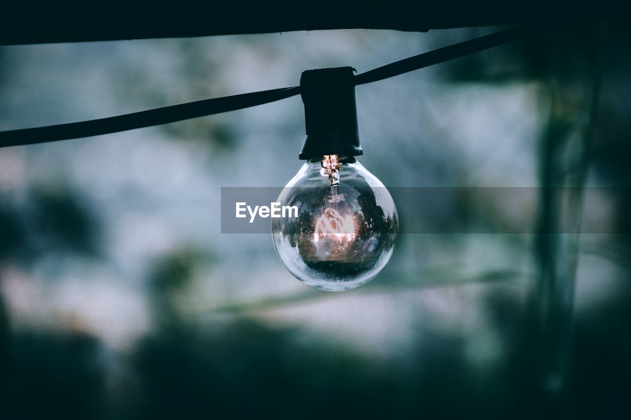 LOW ANGLE VIEW OF LIGHT BULBS HANGING FROM METAL