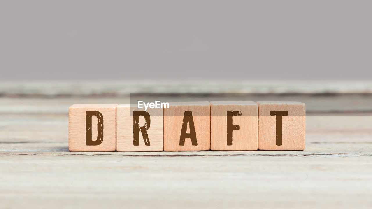 Word draft on wood cube dices on aged table.