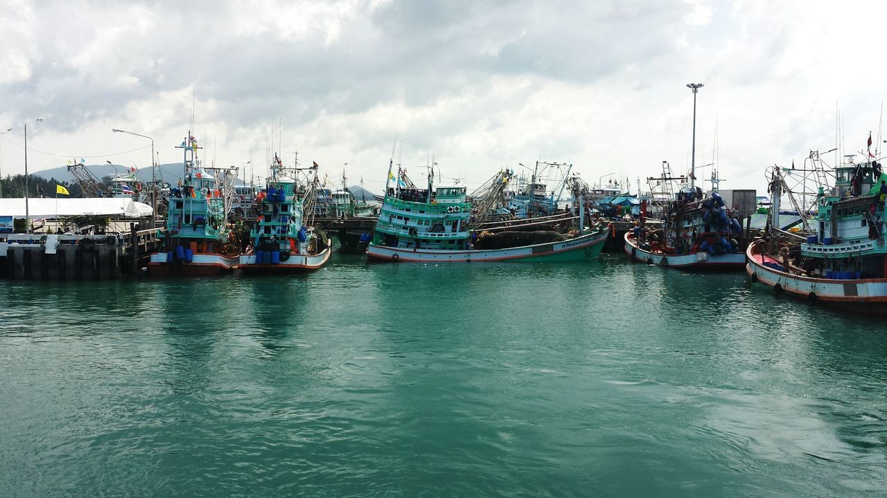 Boats in sea against cloudy sky