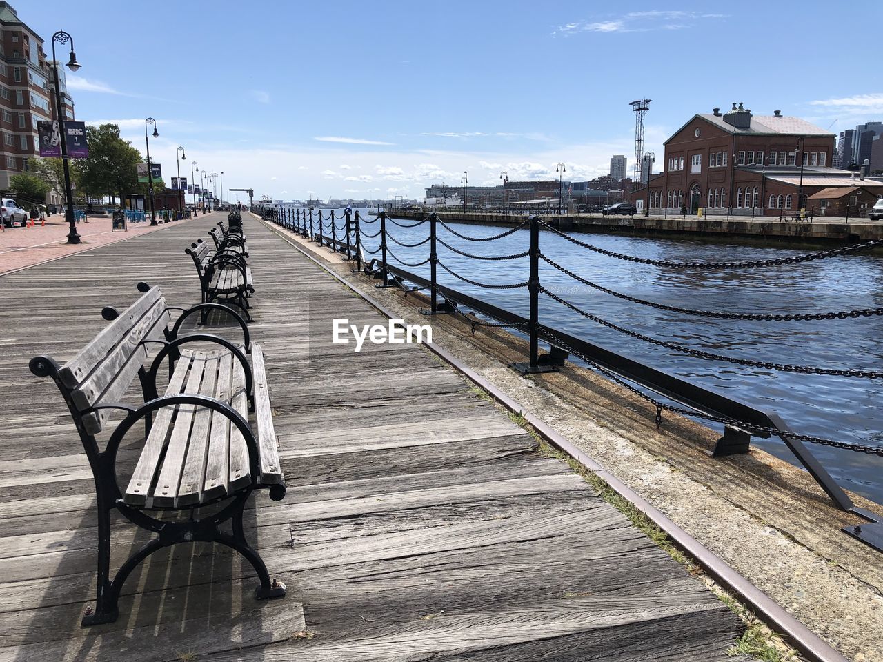 A row of benches next to the waterside at the harbor of boston