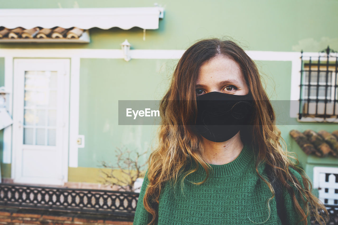 Portrait of woman standing against built structure