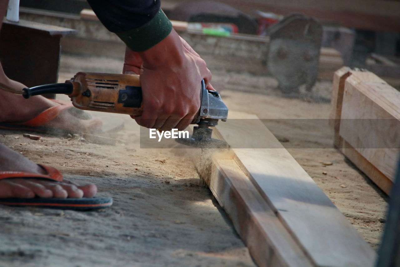 Low section of man working on wood in workshop