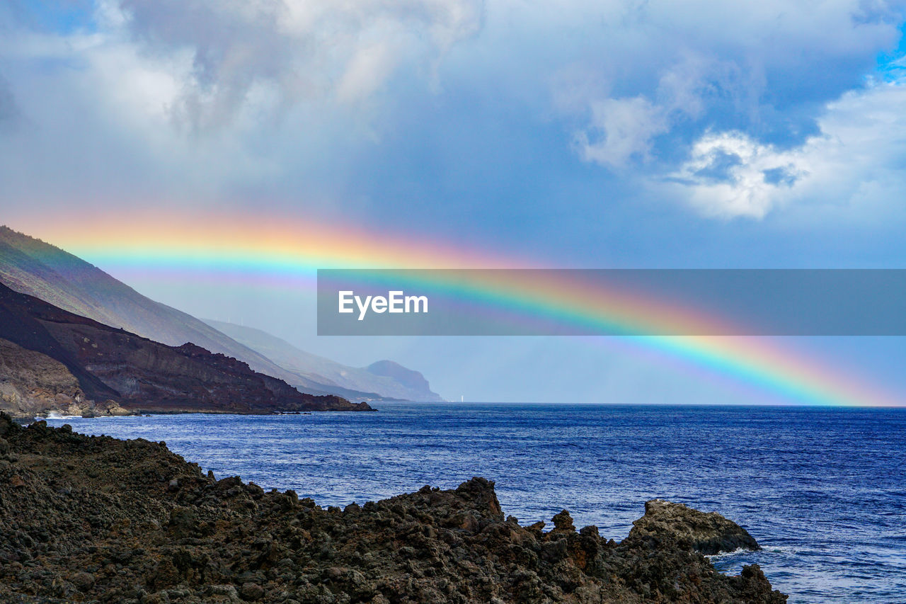 Scenic view of rainbow over sea against sky