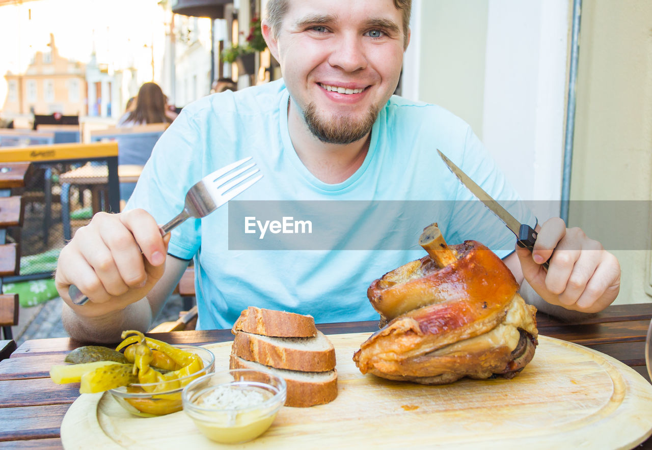 PORTRAIT OF SMILING MAN HAVING FOOD ON TABLE